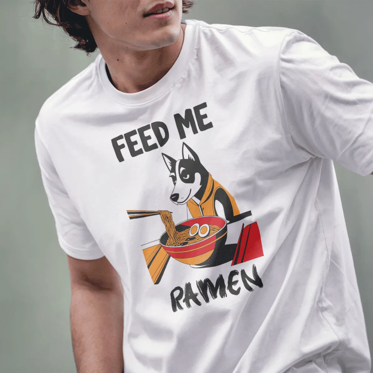 Male model wears white t-shirt with ramen husky, orange hoodie, and “FEED ME RAMEN” text, ramen shirt, cozy food.