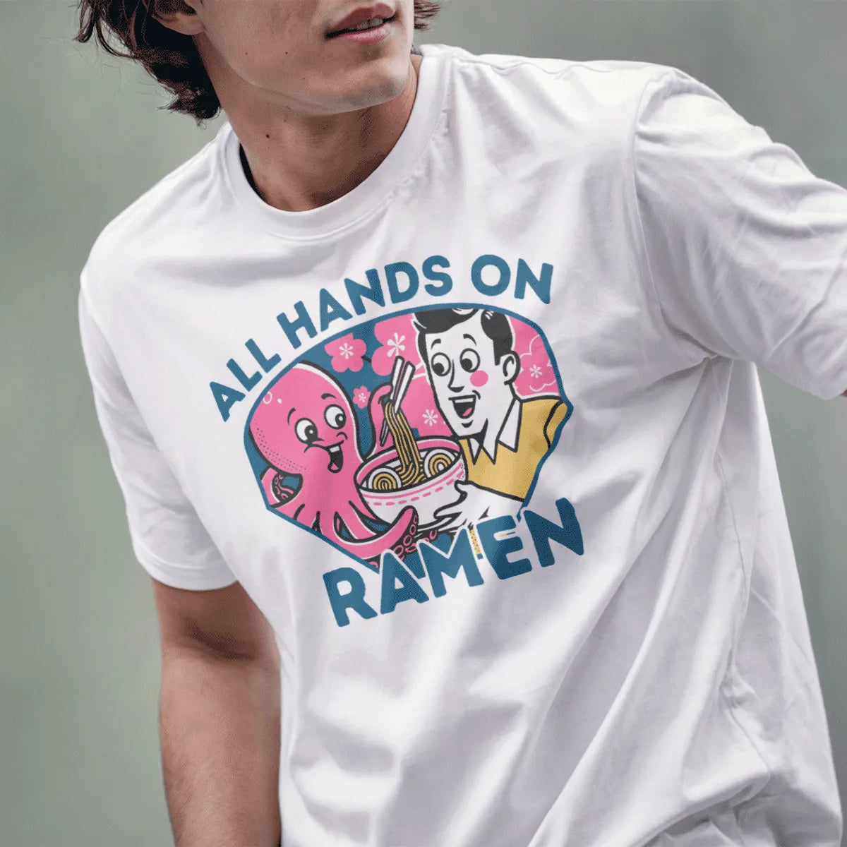 Male model in white shirt with happy octopus and man eating ramen, featuring bold “ALL HANDS ON RAMEN” text.