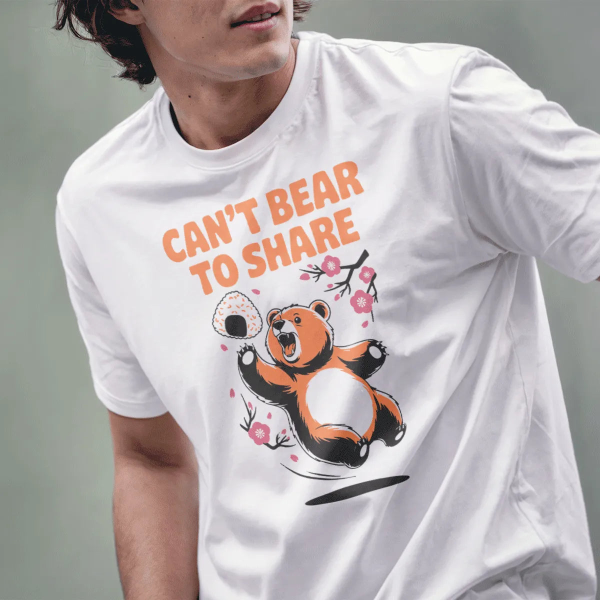 Male model in white t-shirt with whimsical bear, rice ball, cherry blossoms, and "CAN'T BEAR TO SHARE" text, bear shirt.