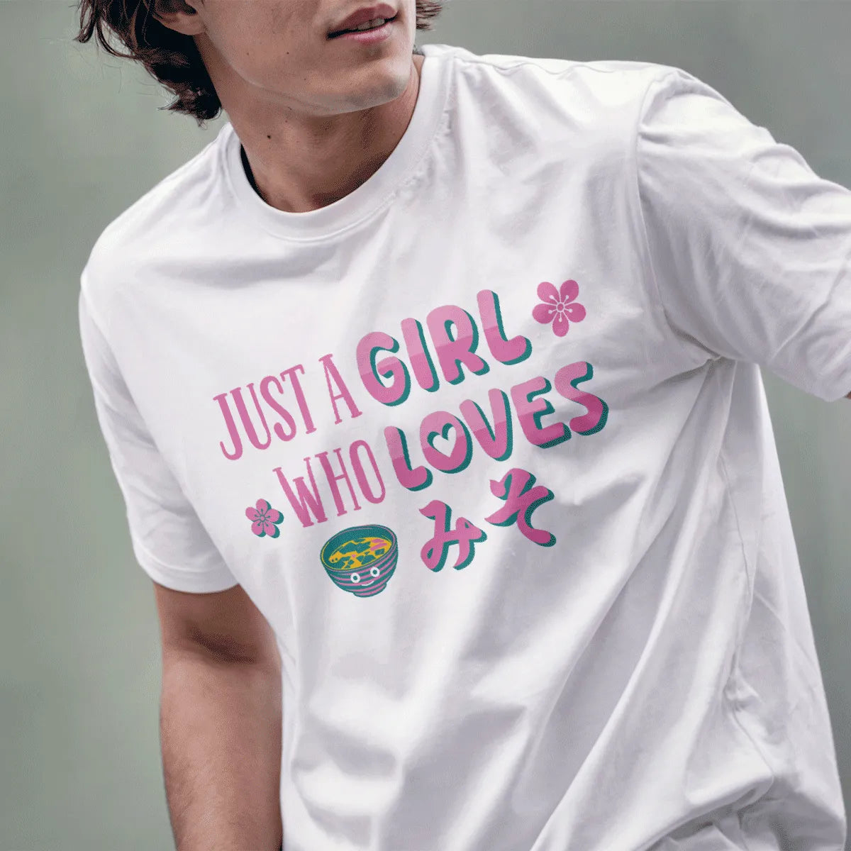 Male model in white miso t shirt with playful pink and teal text, smiling miso bowl, and cherry blossom accents.