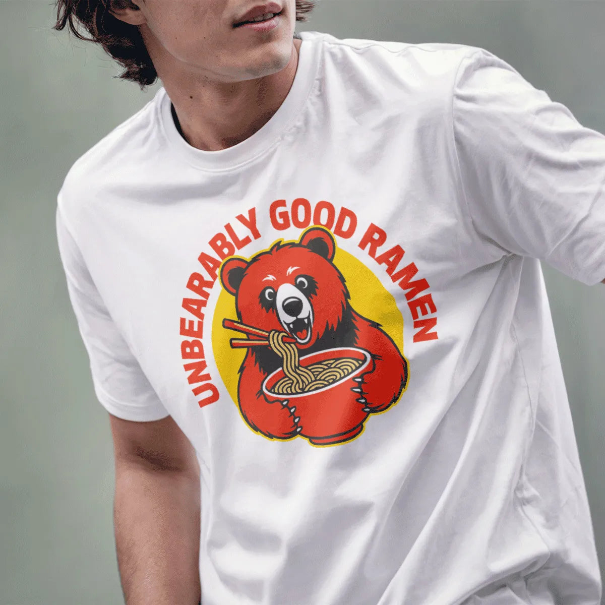 Male model in white t-shirt with cheerful red bear and ramen bowl, ramen t-shirt, cartoonish style.