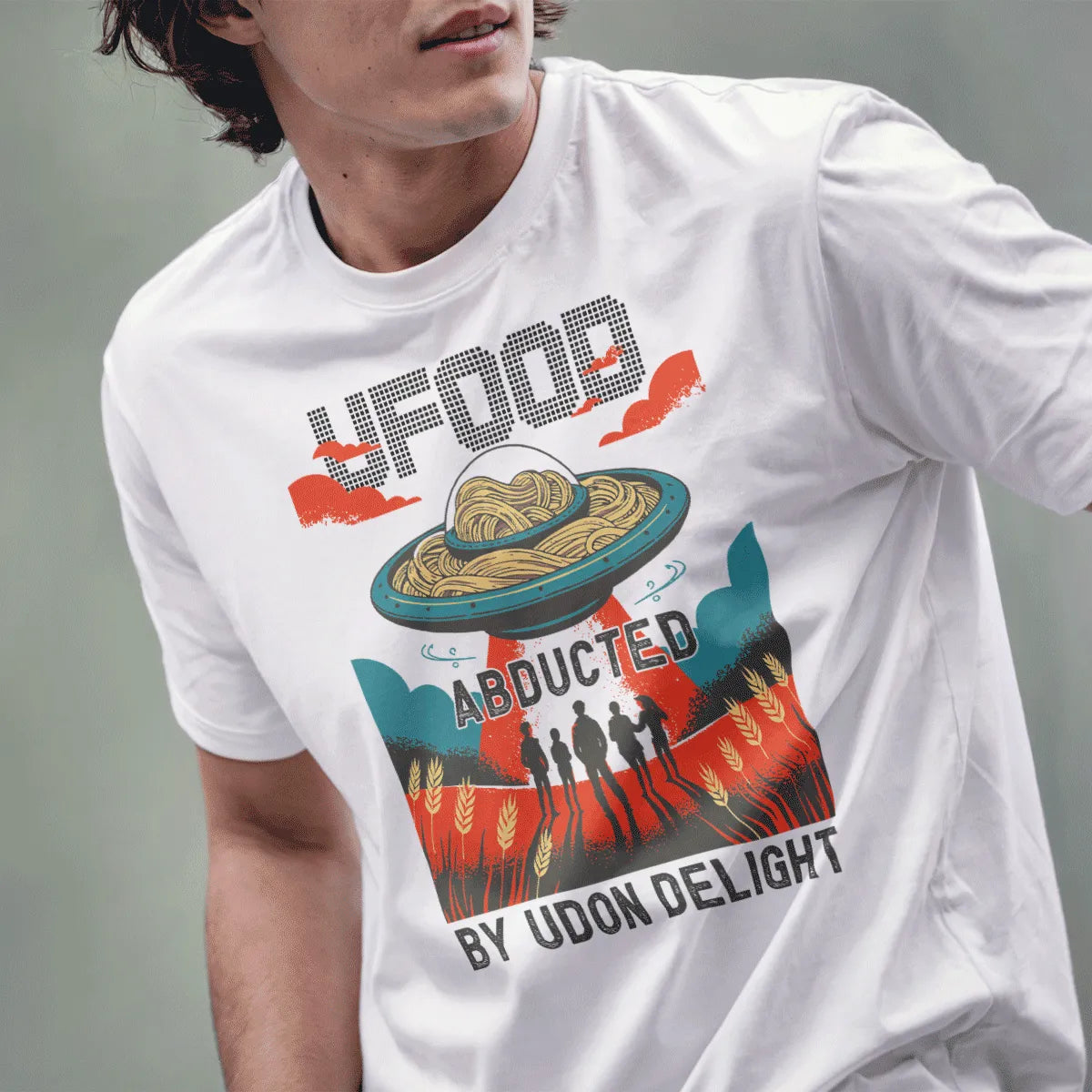 Male model wears white t-shirt with graphic UFO beaming red light, udon noodles, and vintage poster accents.