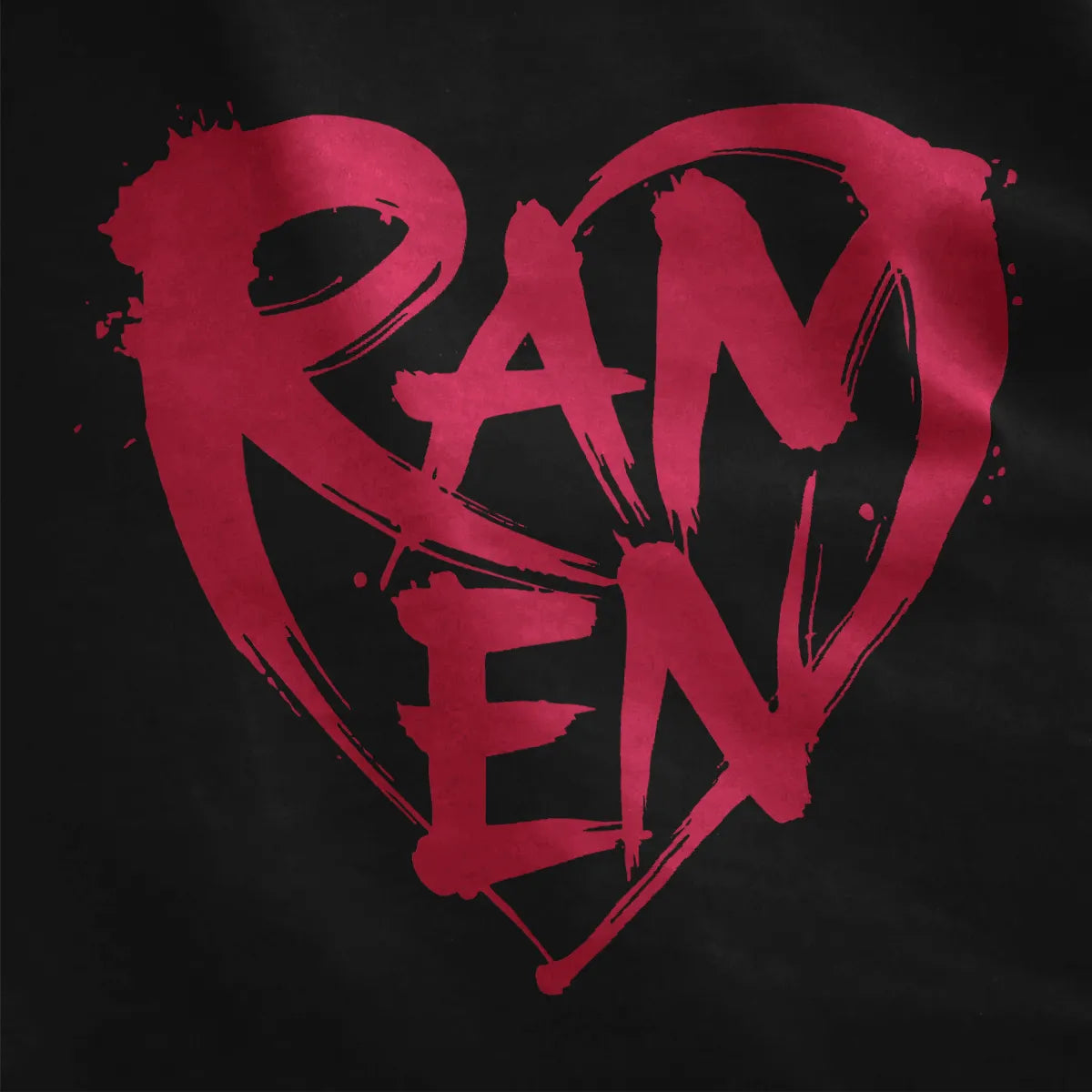 Red RAMEN graffiti lettering with heart and paint splatter on black shirt fabric, urban and bold streetwear style.