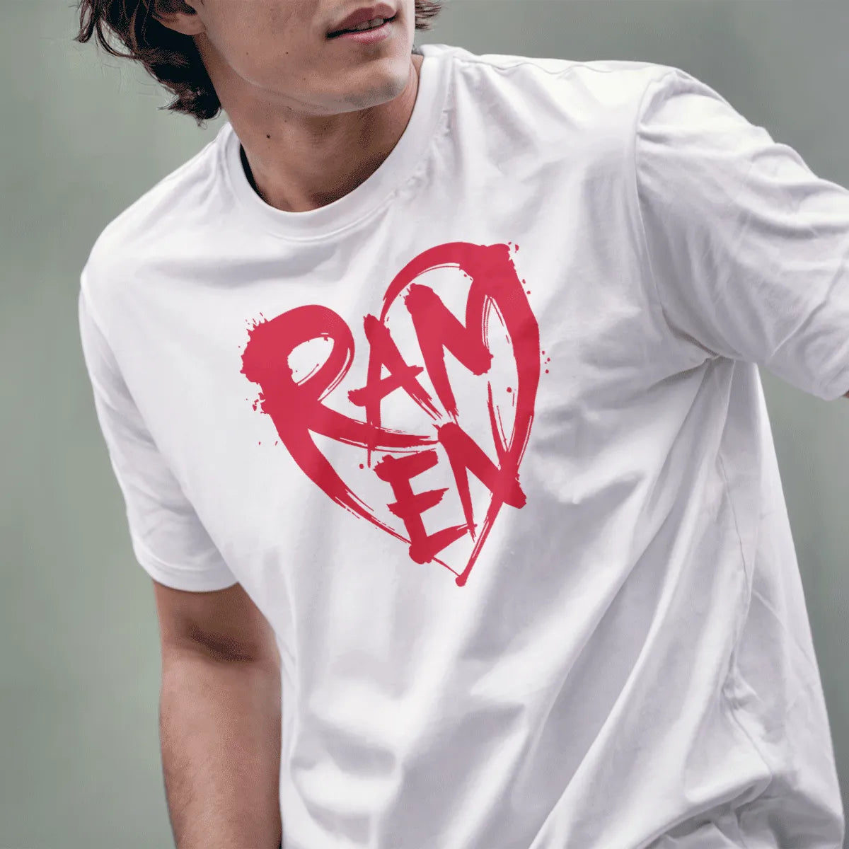 Male model in white t-shirt with bold, hand-drawn red RAMEN heart graphic, paint splatter, and energetic look.