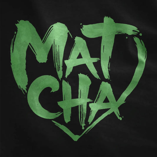 Green brushstroke "Matcha" heart with textured, hand-painted script on black fabric close-up.