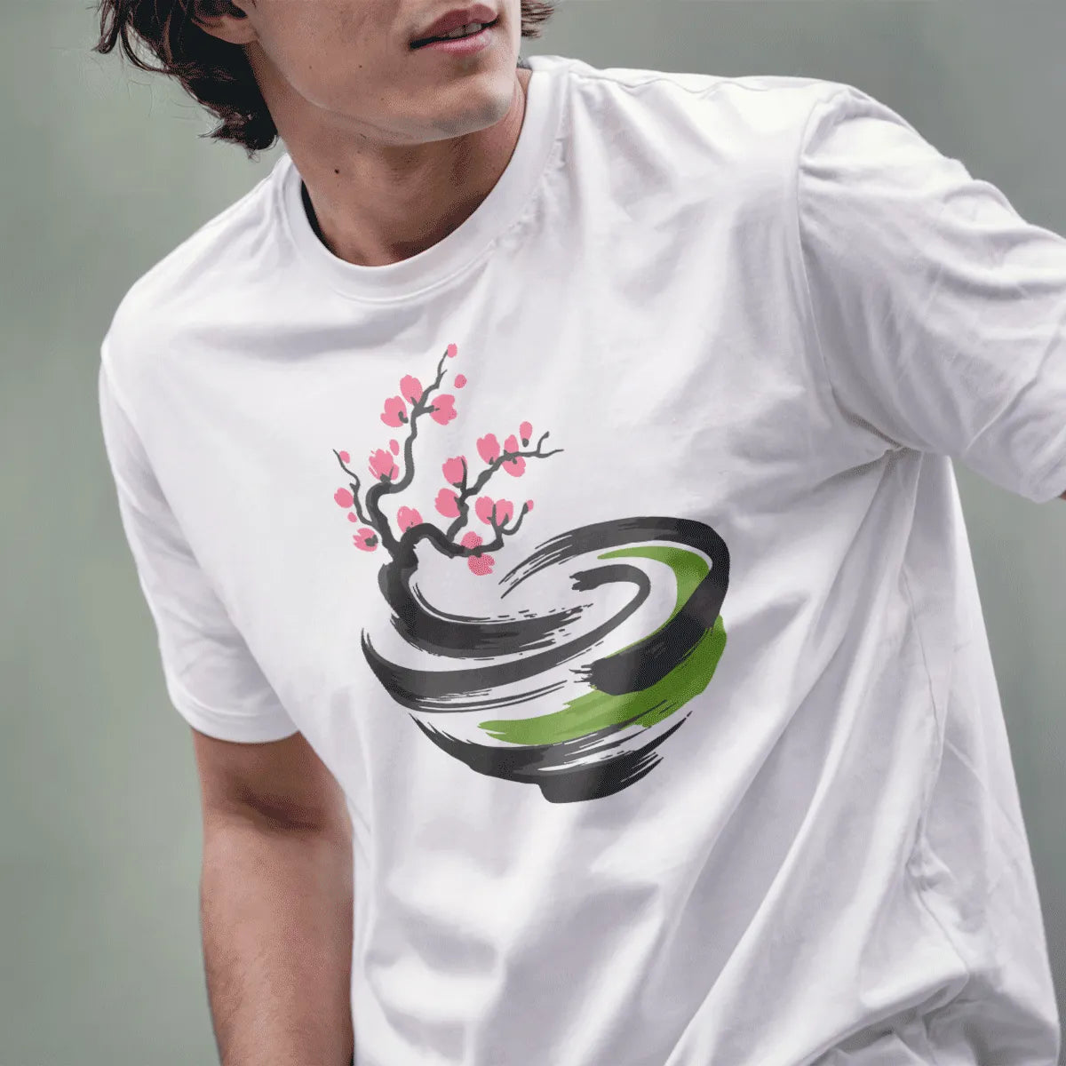 Male model wears white tee with minimalist cherry blossom branch and swirling bowl in pink and grey.