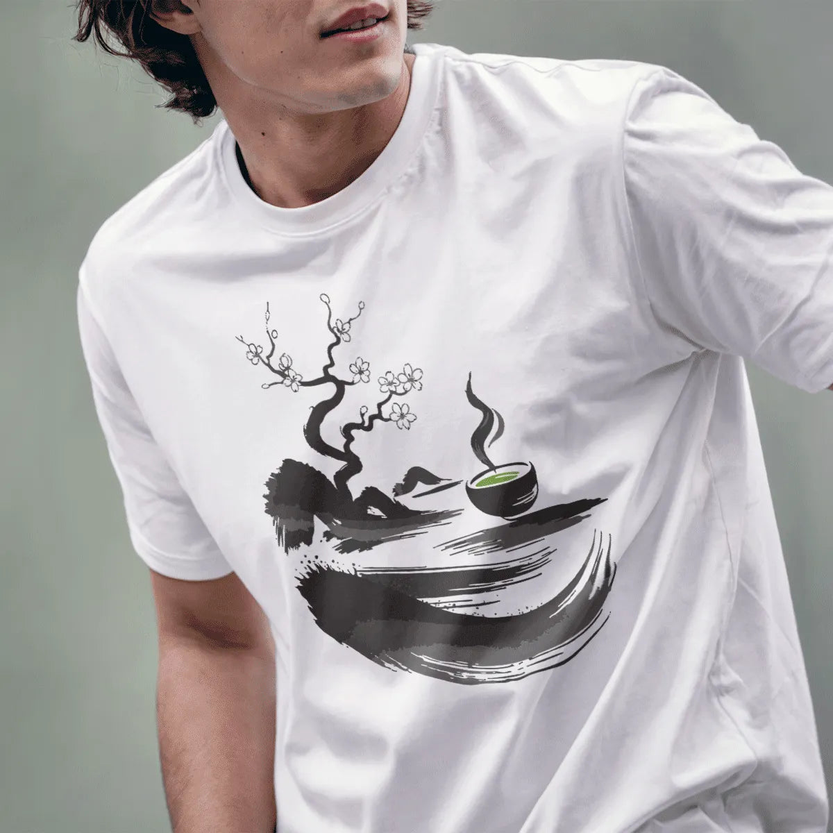 Male model wearing white t-shirt with sumi-e twisted tree, cherry blossoms, and green matcha bowl design.
