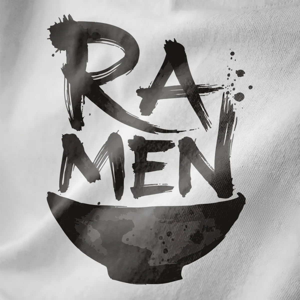 Close-up of black fabric showing bold brushstroke "RAMEN" text above textured ramen bowl.