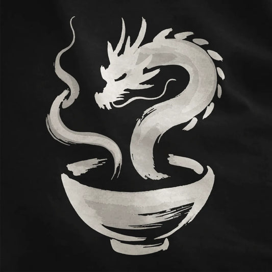 Close-up on black fabric with hand-drawn dragon swirling over ramen bowl in sumi-e brushstroke style.