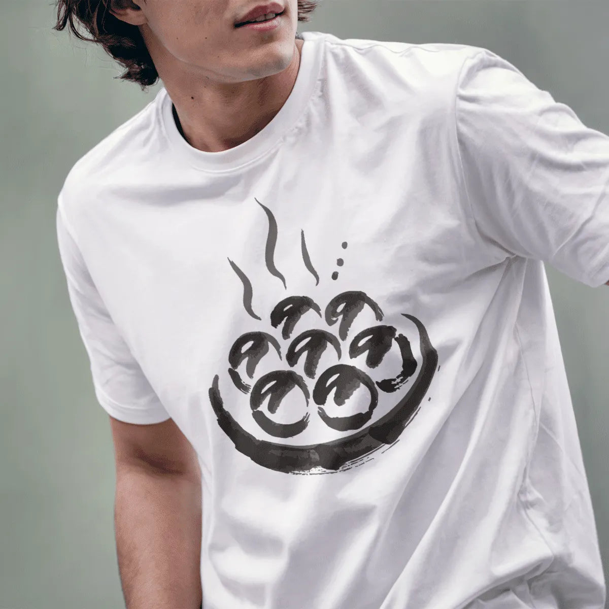 Male model wears white t-shirt with textured takoyaki graphic, blending artistic brush strokes and cozy food theme.