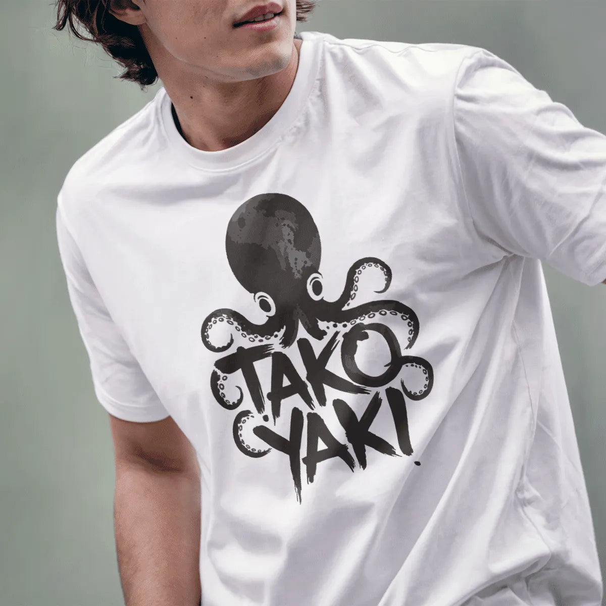 Male model wearing white t-shirt with cheerful octopus wrapped around takoyaki text, kawaii sushi design.