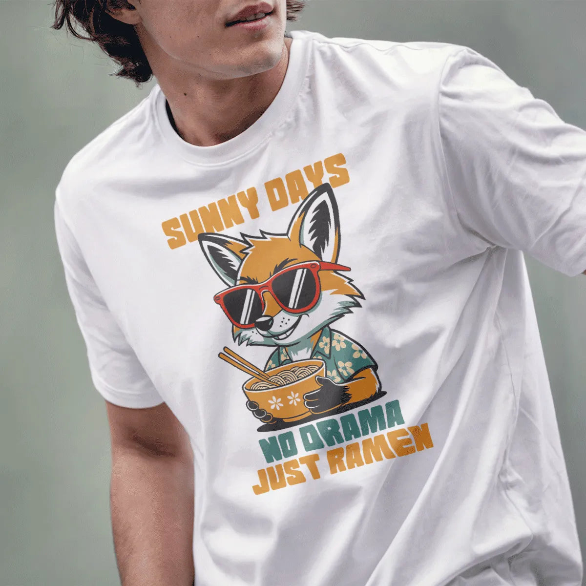Male model in white t-shirt with a fox in teal shirt and ramen bowl design, showing chill vibe and casual style.