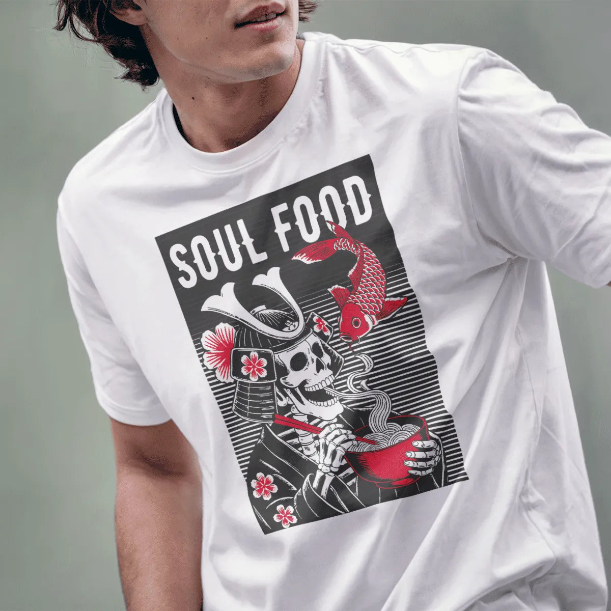 Male model wearing white t-shirt featuring graphic samurai skeleton eating ramen, accented with cherry blossoms.