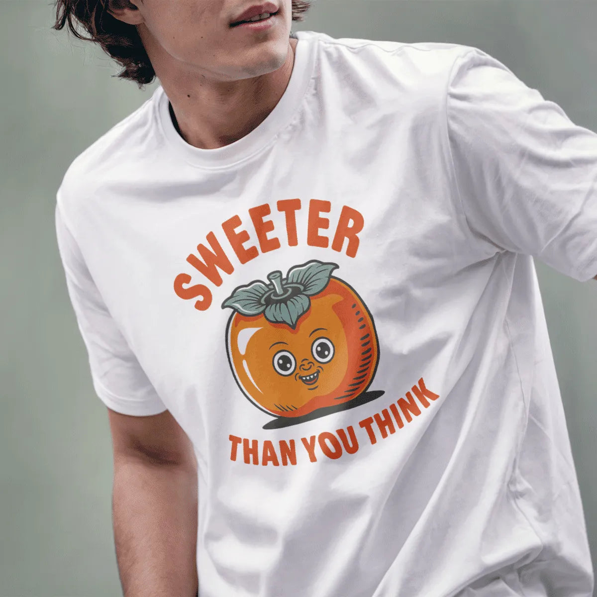 Male model wears white tee with smiling persimmon graphic, bold text "SWEETER THAN YOU THINK," retro vintage style.