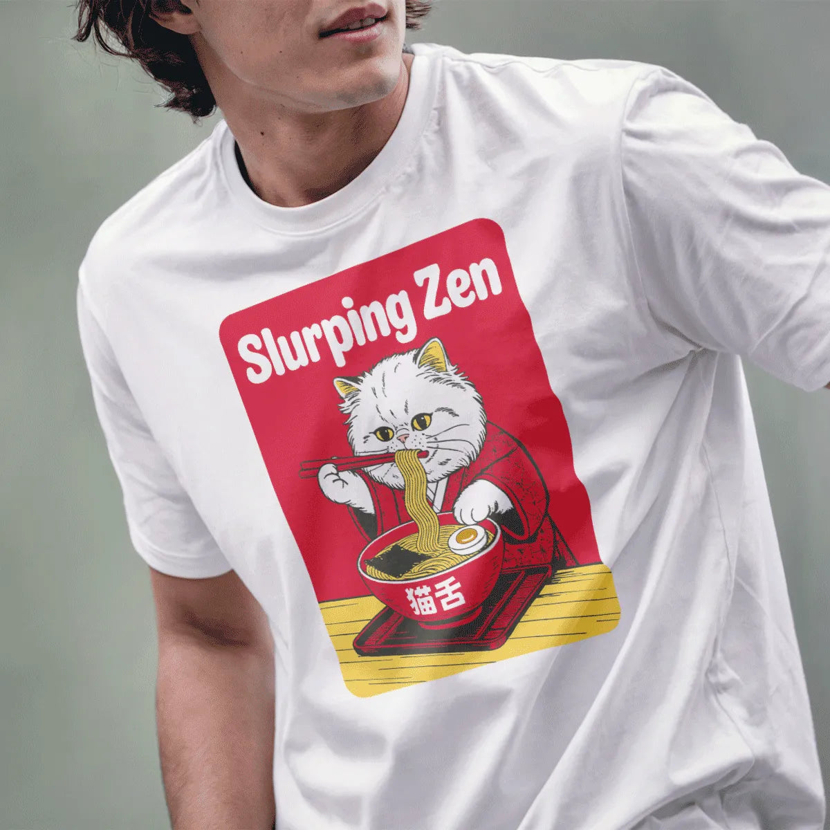 Male model in white tee featuring fluffy white cat with red kimono and steaming bowl of ramen.