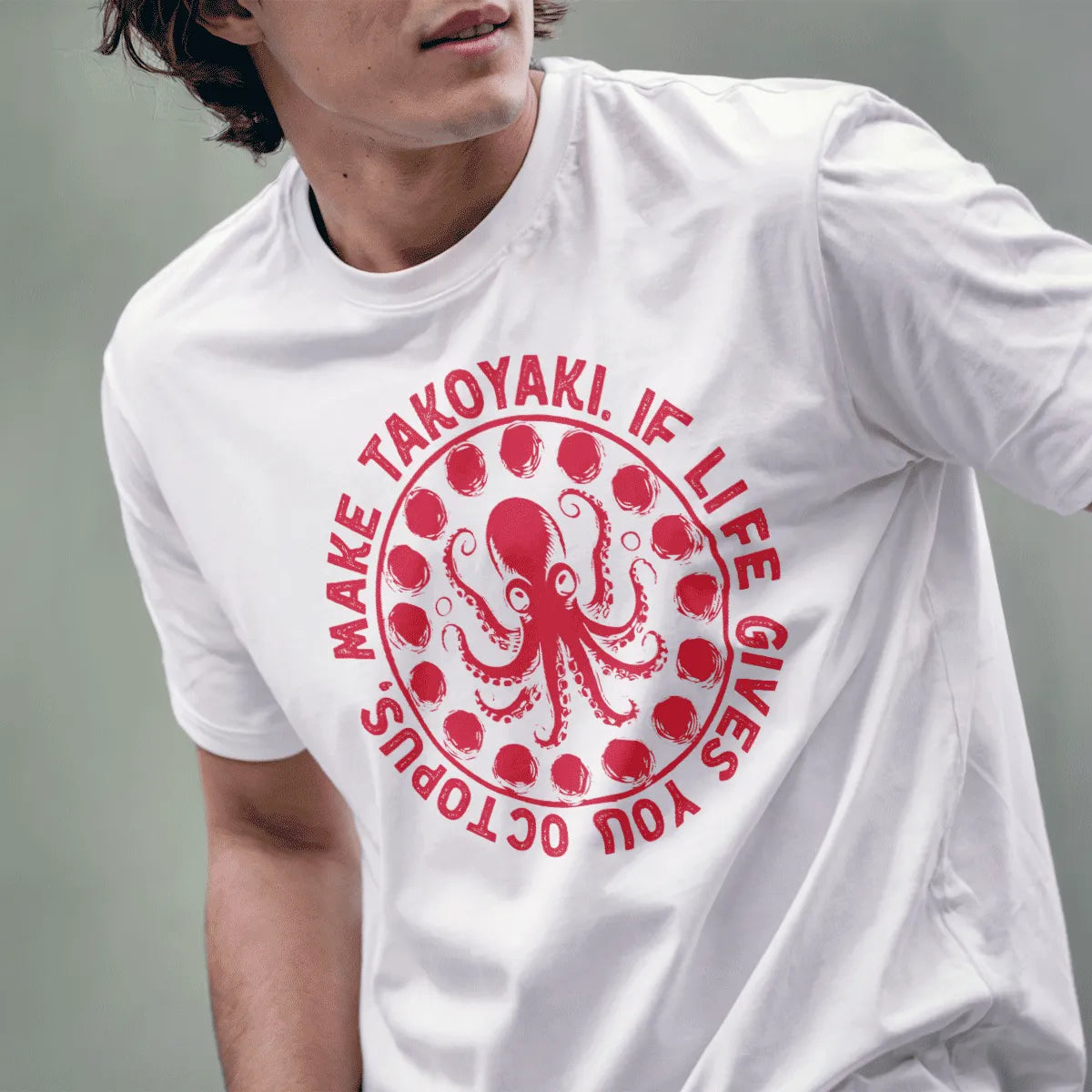 Male model in white t-shirt featuring whimsical octopus and takoyaki design, circular text, graphic tees stores.