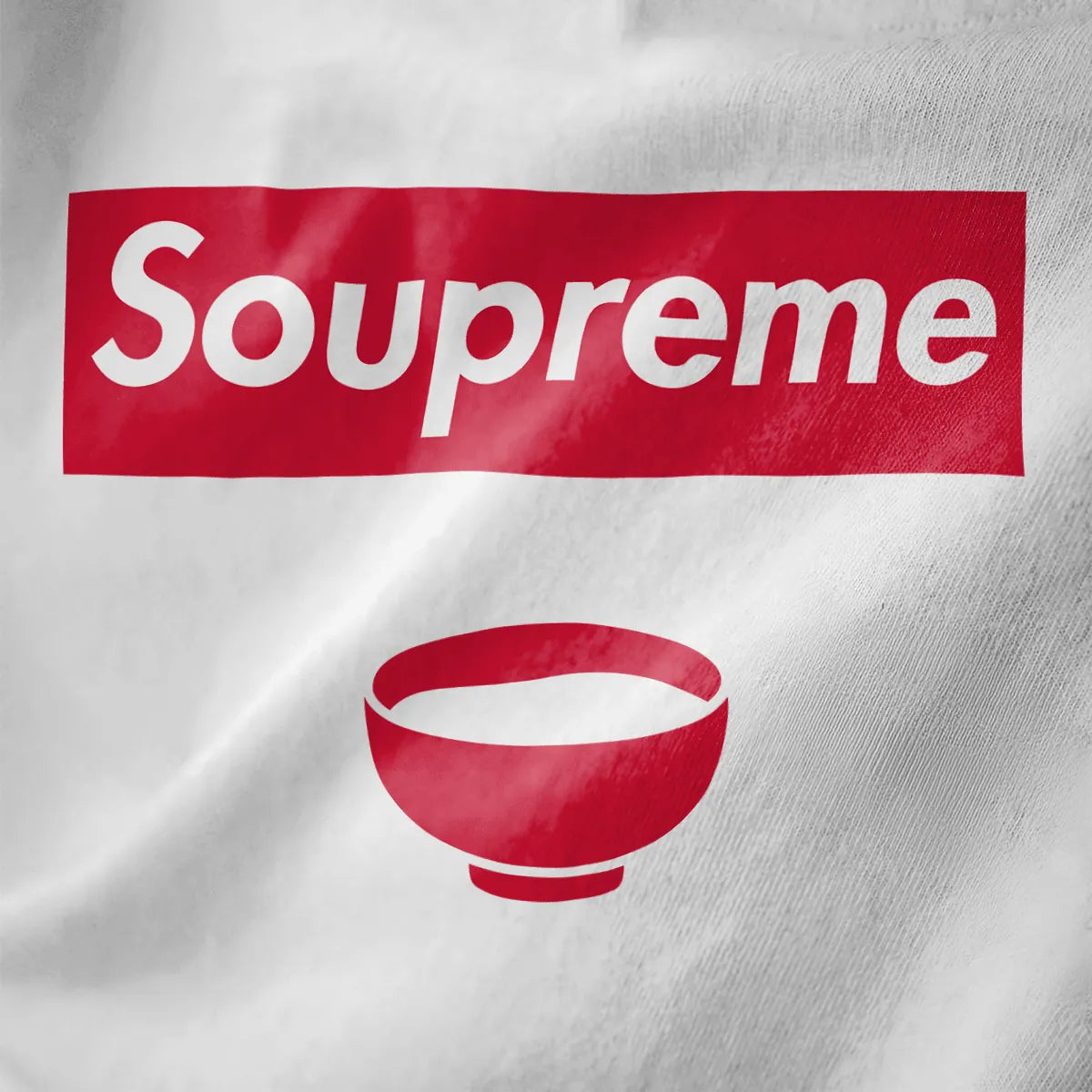 White t-shirt fabric close-up featuring bold Soupreme logo parody and red soup bowl, modern streetwear style.