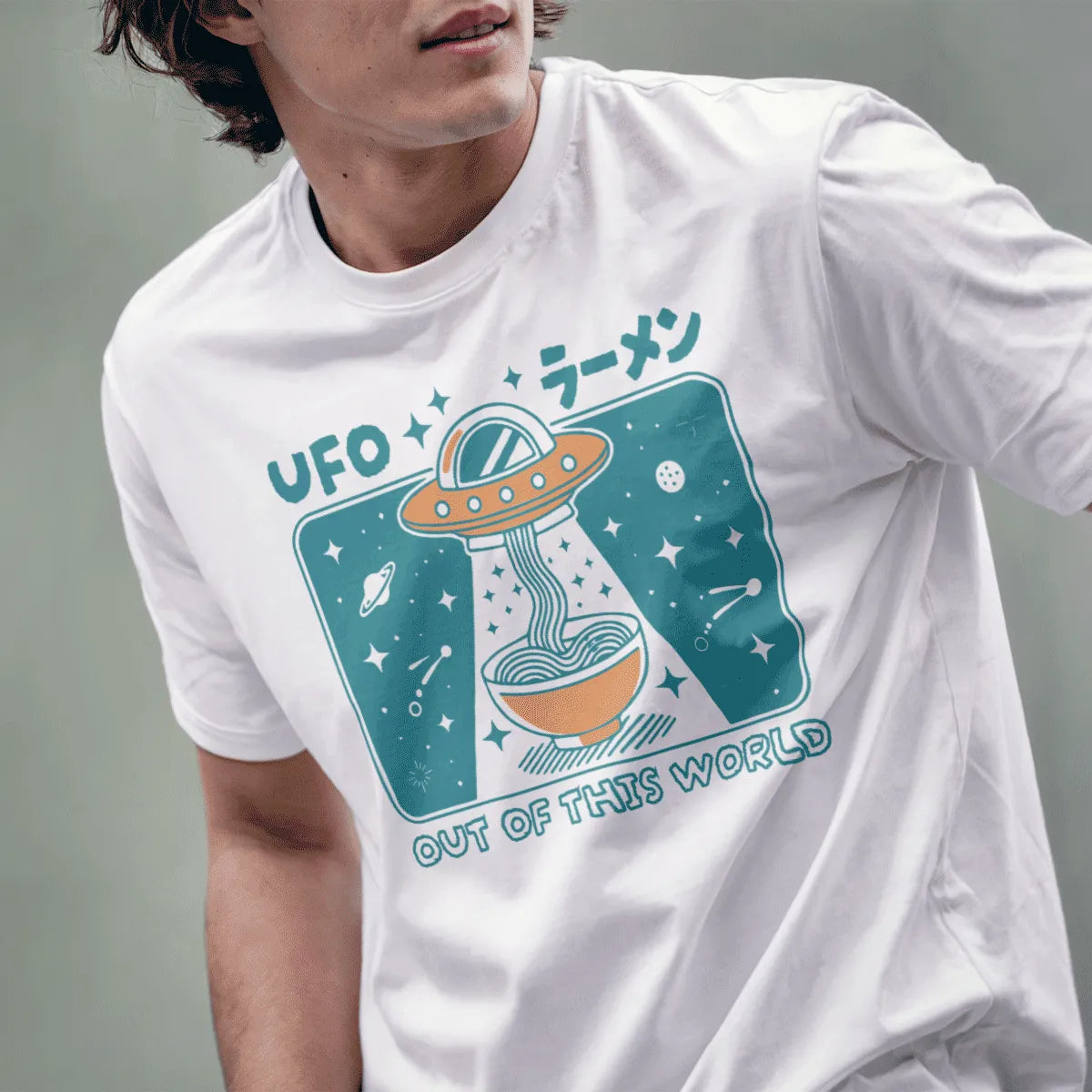 Male model in white t-shirt with cartoonish UFO ramen graphic, bold "OUT OF THIS WORLD" text visible.