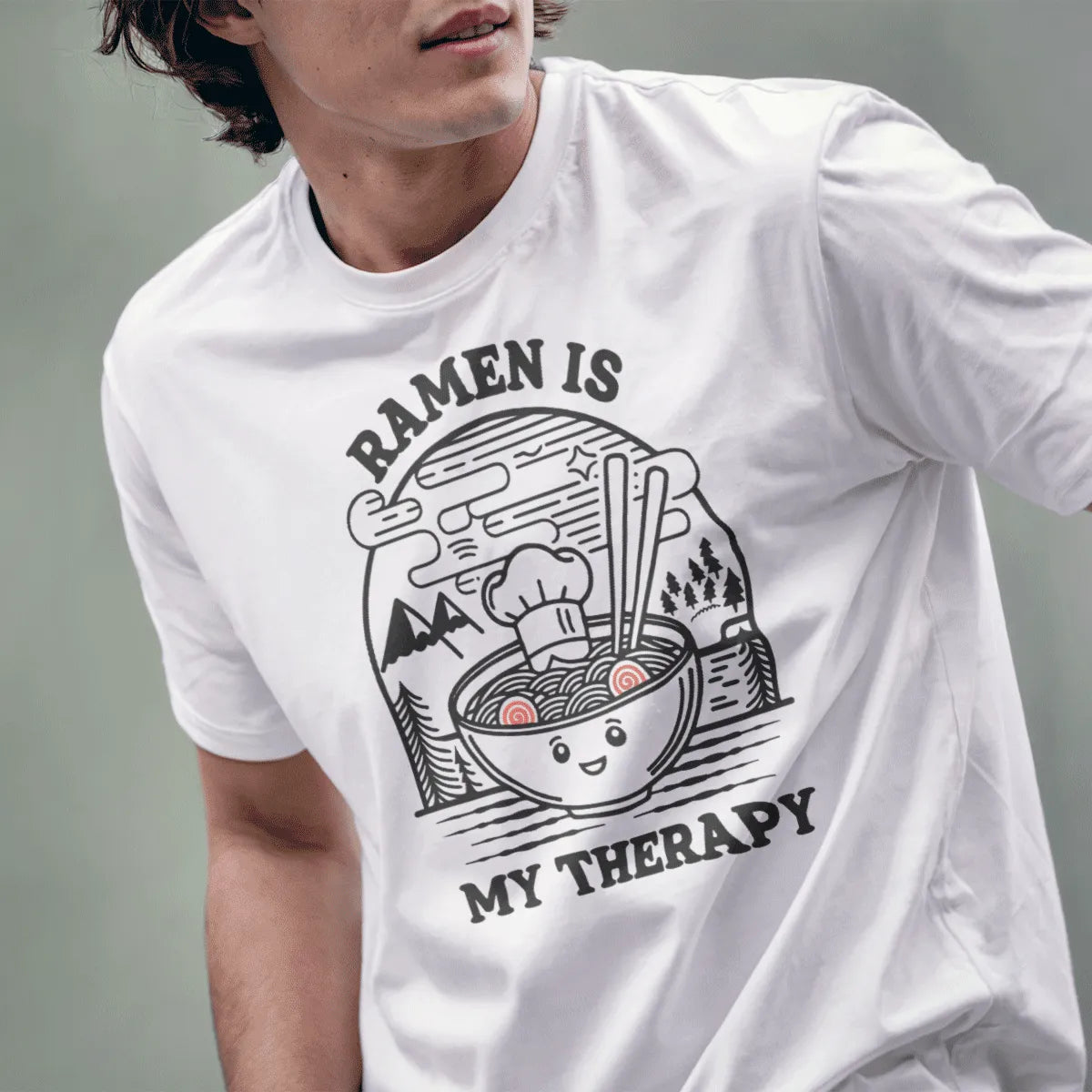 Male model wears white t-shirt with cheerful ramen bowl and "RAMEN IS MY THERAPY" slogan, cozy food, motivational quote.