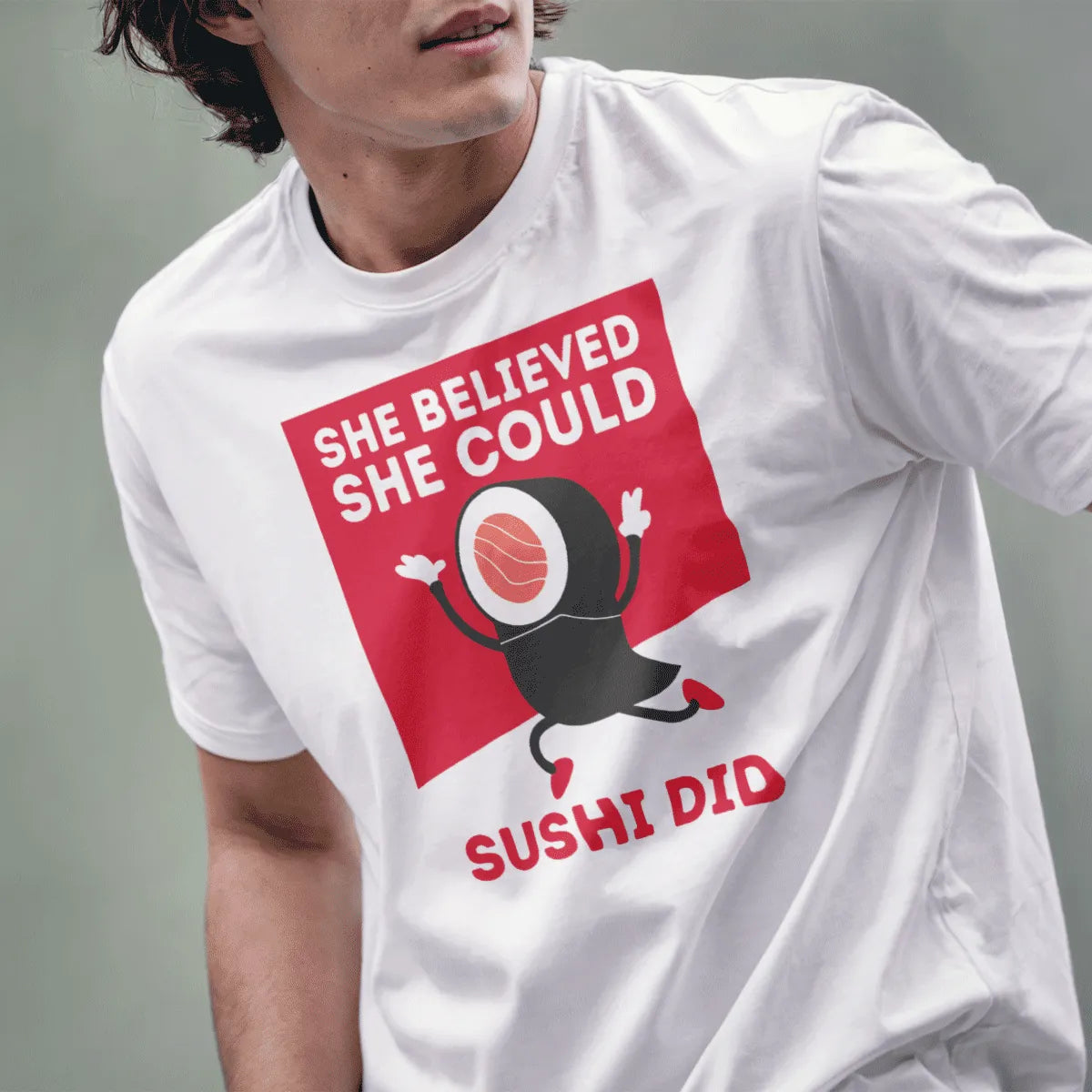 Male model in white sushi t-shirt with empowering “She Believed She Could Sushi Did” phrase, lower face visible.