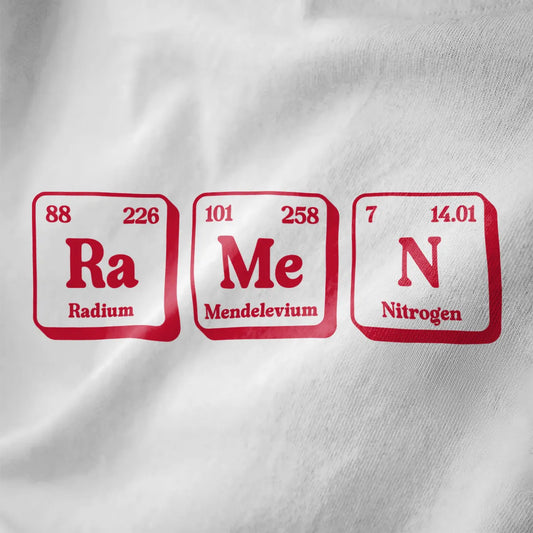 Close-up of red and white periodic table ramen shirt on white fabric, featuring bold text and playful graphic design.