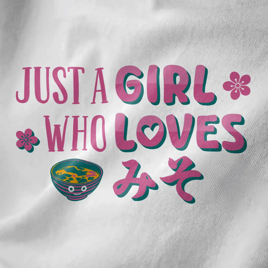 White closeup of miso shirt with pink and teal hand-drawn text, cherry blossoms, and smiling miso soup bowl.