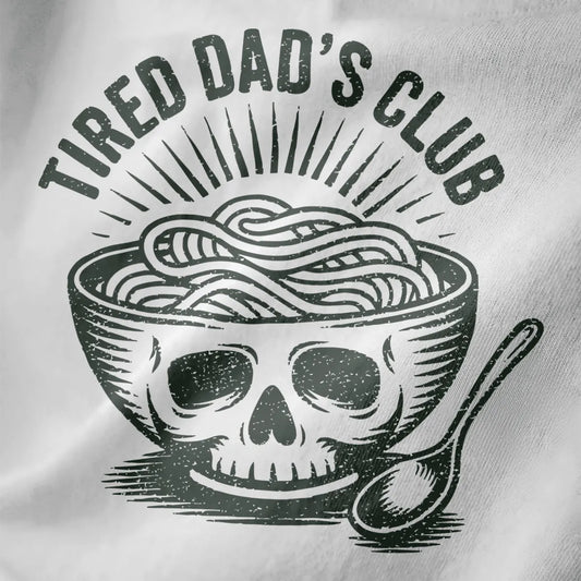 Distressed black and white ramen bowl with skull motif and "TIRED DAD'S CLUB" text on white fabric close-up.