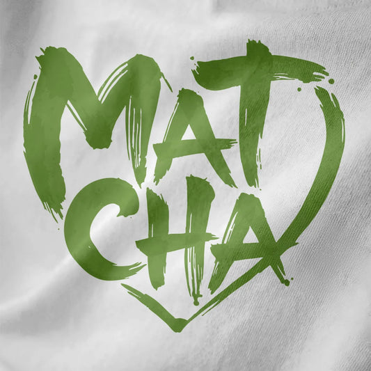 Close-up of vibrant green brushstroke "Matcha" text shaped into a dynamic heart on white fabric.