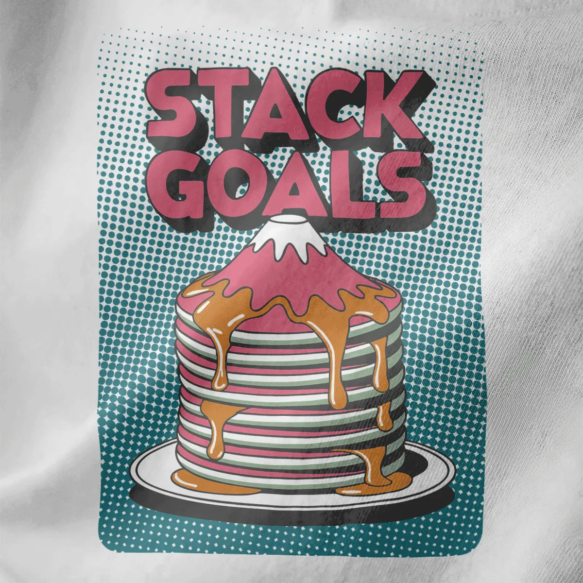 Close-up of pink and white pancake stack shaped like Mount Fuji with syrup and teal pop-art background on white fabric.