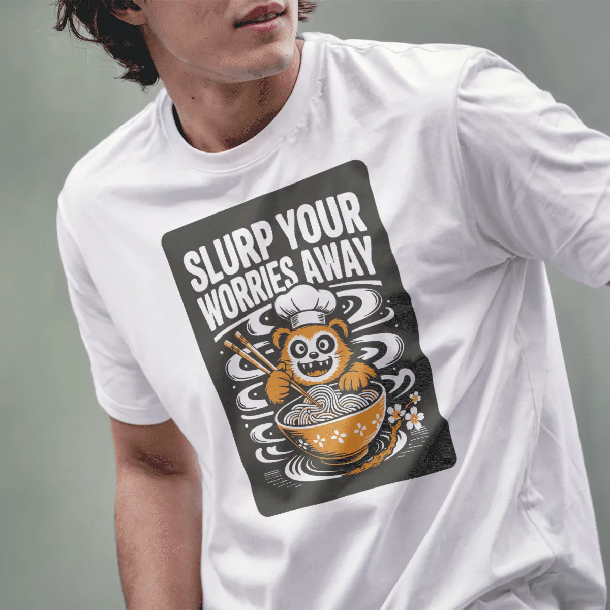 Male model wearing white tee with kawaii red panda happily slurping ramen from floral bowl.