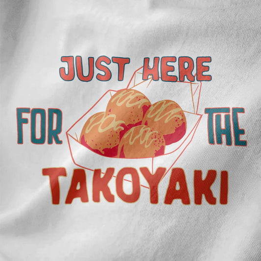 White fabric close-up of takoyaki t-shirt with bold, colorful "JUST HERE FOR THE TAKOYAKI" text, vibrant style.