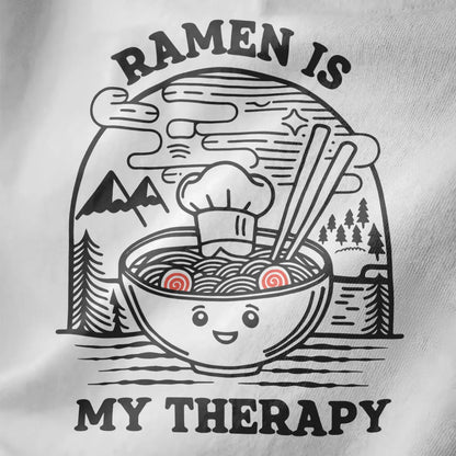 Close-up of playful ramen t-shirt design on white fabric, featuring cozy food and serene landscape details.