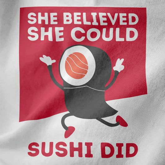 Close-up of white shirt with sushi roll character and “She Believed She Could Sushi Did” motivational quote.